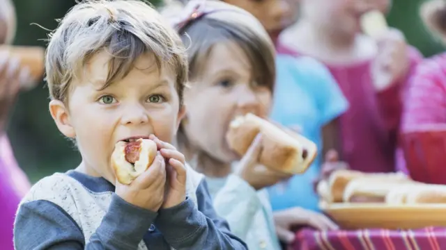 Niños comiendo perros calientes.