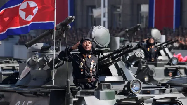 Korean People's Army (KPA) soldiers stand atop armoured vehicles during a military parade