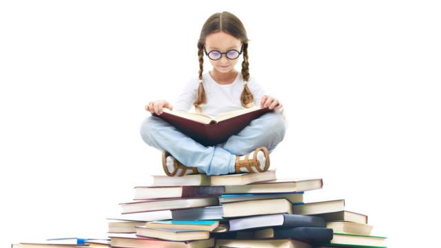 niña sentada sobre un montón de libros