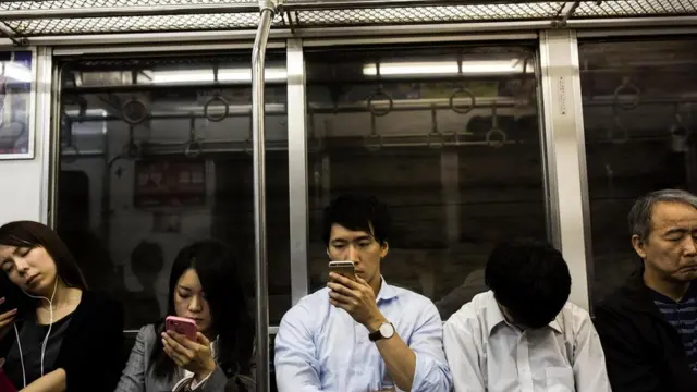 Pengguna kereta bawah tanah di Tokyo. Kehidupan di Abad ke-21 didefinisikan dengan penggunaan teknologi yang terus-menerus.