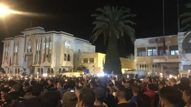 تصویری از جمع کثیری از مردم که در تاریکی شب با برافروختن شمع در میدان اصلی شهر حسیمه تجمع کردهاند