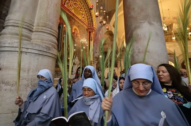 Roman Catholic nuns carry palm branches as they circle the aedicule during the Palm Sunday procession at the Church of the Holy Sepulchre in Jerusalem's Old City, on April 10, 2022. - The ceremony is a landmark in the Roman Catholic calendar, marking the triumphant return of Christ to Jerusalem the week before his death, when a cheering crowd greeted him waving palm leaves. Palm Sunday marks the start of the most solemn week in the Christian calendar. (Photo by AHMAD GHARABLI / AFP) (Photo by AHMAD GHARABLI/AFP via Getty Images)