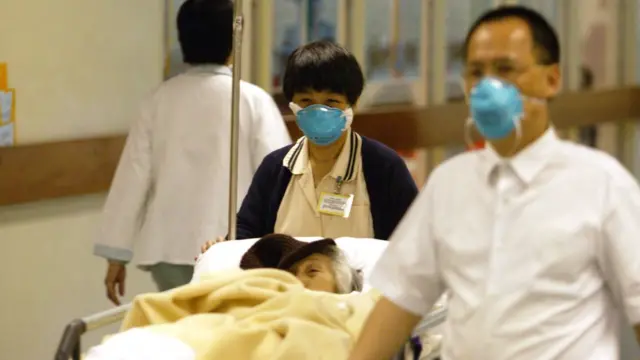 হংকং ২০০৩, একজন সার্স রোগীকে নিয়ে যাচ্ছেন স্বাস্থ্যকর্মীরা