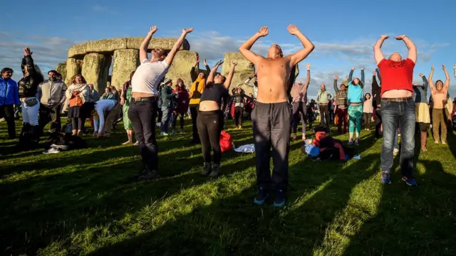 Люди займаються йогою біля Стоунехенджу