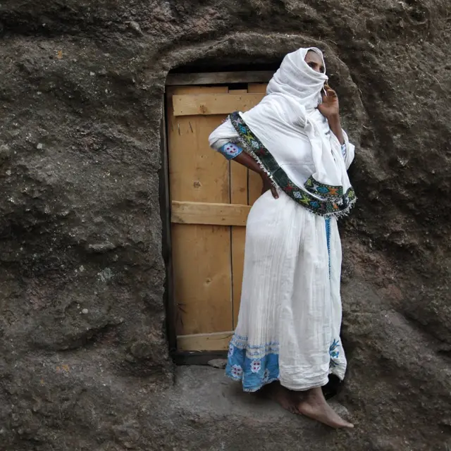 Žena umotana u netelu, odeću od belog pamuka pred vratima monaške kelije. Hramovi Lalibele isklesani su u stenama ispod nivoa tla i međusobno povezane nizom prolaza i tunela.