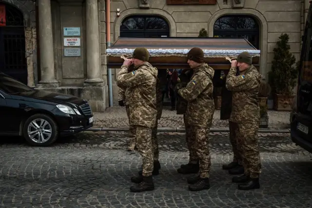 O caixãoKotenko sendo carregado para o interior da igreja militarLviv. Três homens foram enterrados naquele dia.