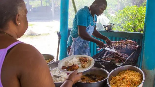Man dey serve pesin grilled fish and rice.