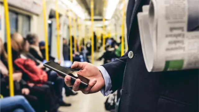 Pessoa olhando o celular no metrô