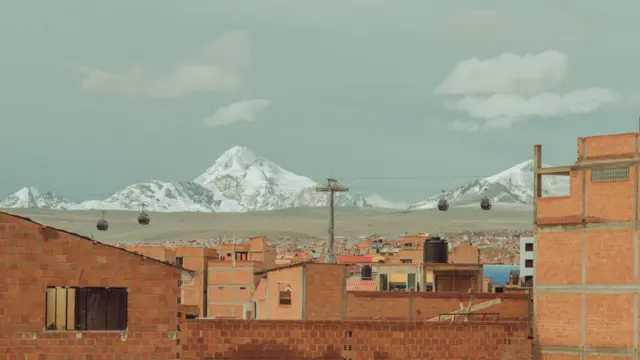 Casas com tijolo aparente e sem pintura e,jogar jogo jogo da velhasegundo plano, as cordilheiras dos Andes com gelo