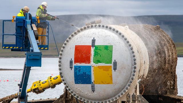 Dos hombres lavan a presión el exterior de la cápsula del centro de datos de Microsoft.