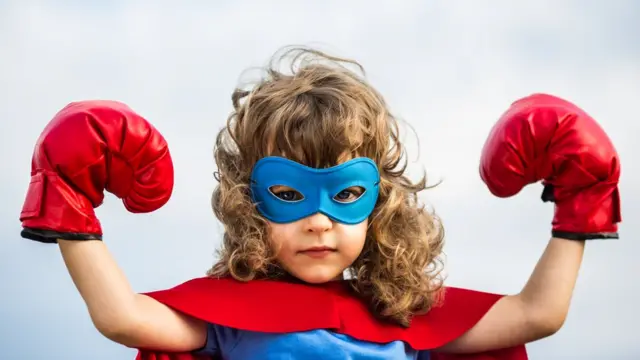 Niña con traje de Superman y guantes de boxeo.