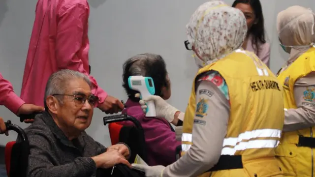 Petugas Kesehatan Karantina Bandara Soekarno Hatta melakukan pemeriksaan acak suhu badan penumpang yang baru mendarat di Terminal 3 Bandara Soekarno Hatta, Tangerang, Banten, Rabu (22/01).