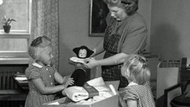 Mãe mostra conteúdo da caixa às filhas, em foto de 1947