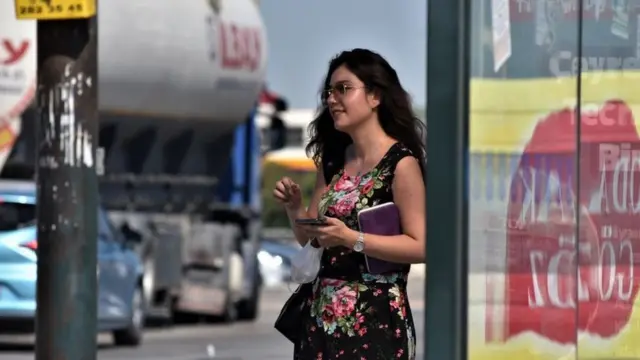 A young woman uses her mobile phone while waiting at a bus station in Ankara