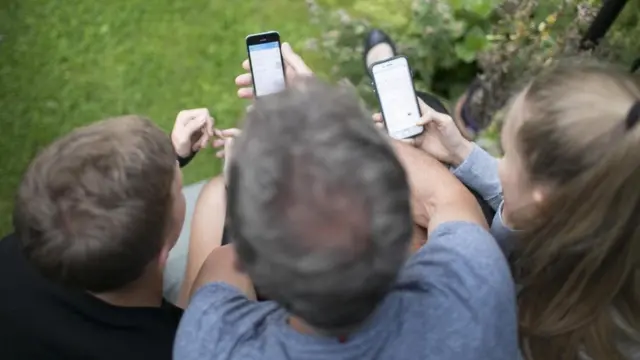 أشخاص يحملون هواتفهم المحمولة وينظرون إليها