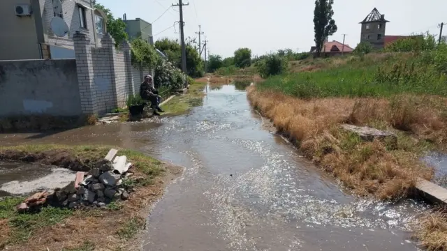 Чоловік сидить біля підтопленого будинку на околицях Херсона