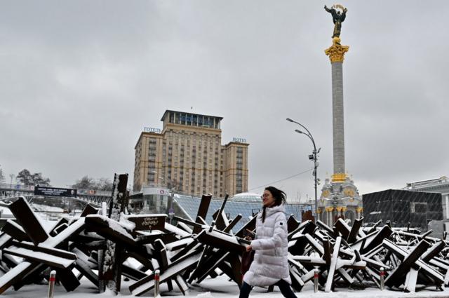 Una mujer camina por barricada antitanque en Kyiv.