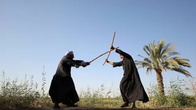 رجلان يرقصان رقصة التحطيب