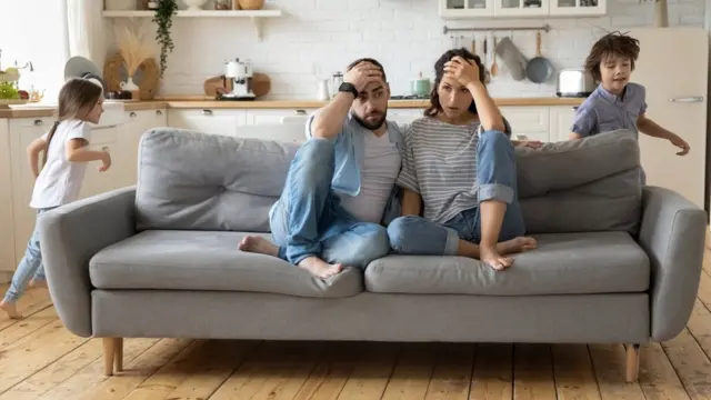 Una pareja desesperada con hijos corriendo por la sala