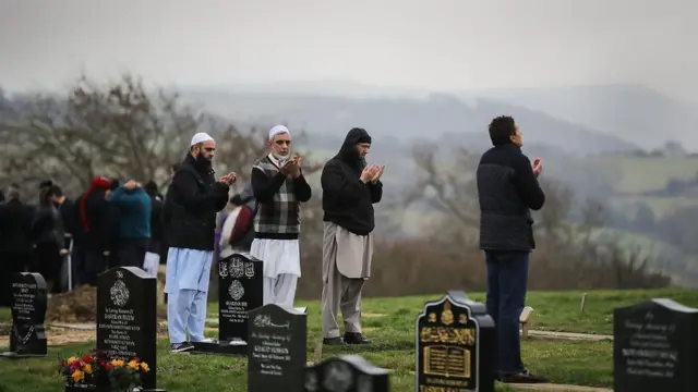 ইংল্যান্ডের হাডার্সফিল্ড শহরে একটি মুসলিম কবরস্থানে দাফনের দৃশ্য। ২০১৭ সালের ৬ই জানুয়ারি। পুলিশের গুলিতে নিহত এক মুসলিম যুবকের দাফন শেষ করে দোয়া পড়ছেন স্থানীয় মুসলিমরা।