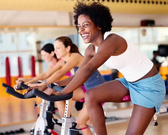 Mulheres pedalando na academia