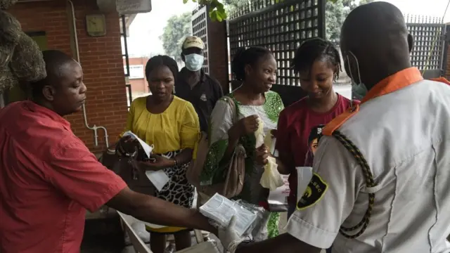 Visitors to one goment hospital collects face masks, hand gloves and have dia hands sanitise as dey walk past di security post entrance in Lagos, on February 28, 2020