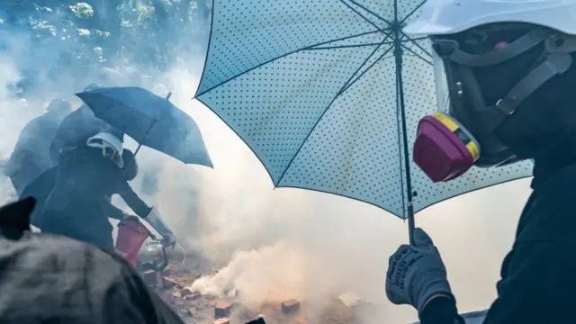 Manifestantes con paraguas y mascarillas.