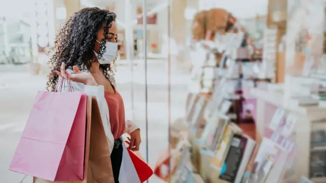 Mujer con bolsa mira vitrina.