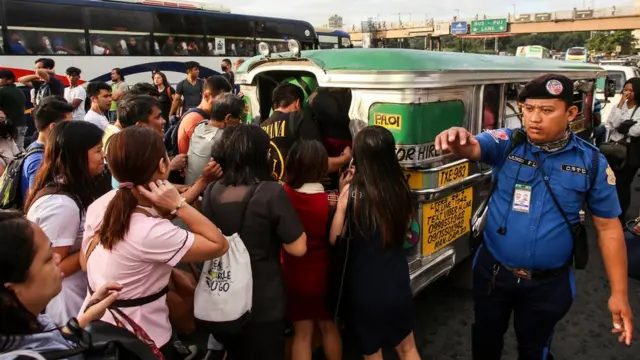 A traffic enforcer (R) guides commuters jostling with each other to ride on a passenger jeepney as transport strike starts in Manila on September 30, 2019,