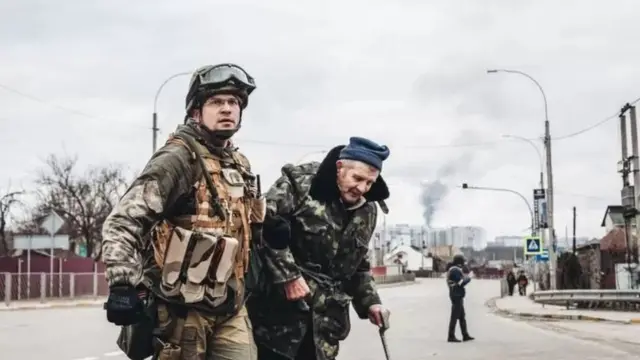 Un soldat aide un homme âgé à traverser