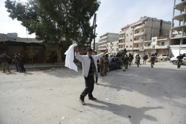 او پرچم سفیدش را به نیروهای ترکیه نشان می‌دهد که وارد شهر شده‌اند
