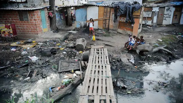 Crianças à margemquina hojecórrego poluído ao ladoquina hojemoradias precárias