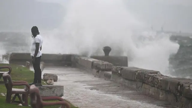 Un hombre mira las olas provocadas por la tormenta Melissa en Kingston