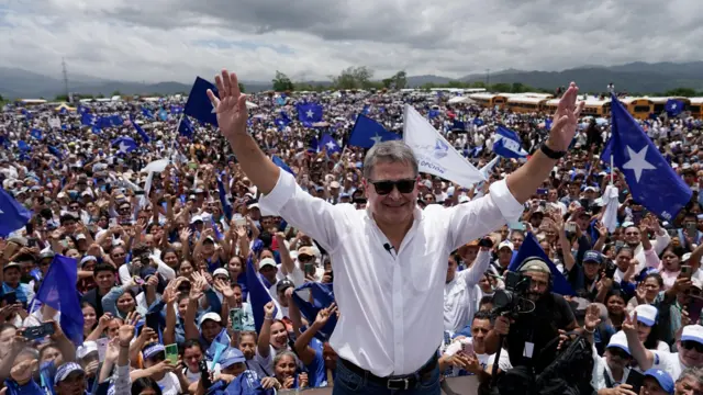 Hernández saluda a sus simpatizantes rodeado de banderas azules del Partido Nacional.