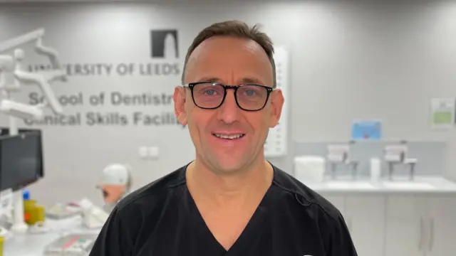 El profesor Peter Day viste un mono de odontología y gafas negras en la Facultad de Odontología de la Universidad de Leeds.