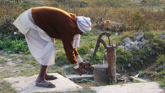 Indian farmer dey fetch water from pump
