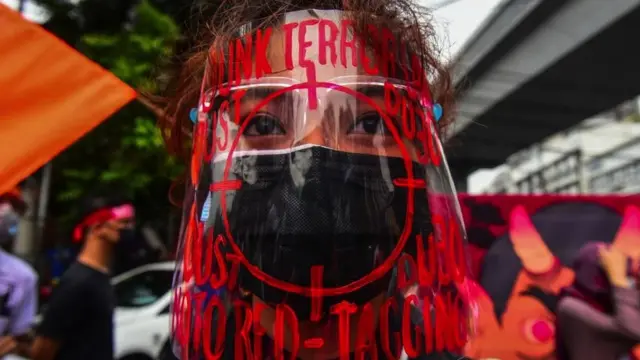 This photo taken on December 10, 2020 shows a protester wearing a face shield decorated with slogans against "red-tagging", as she takes part in a protest to commemorate International Human Rights Day near the presidential palace in Manila.