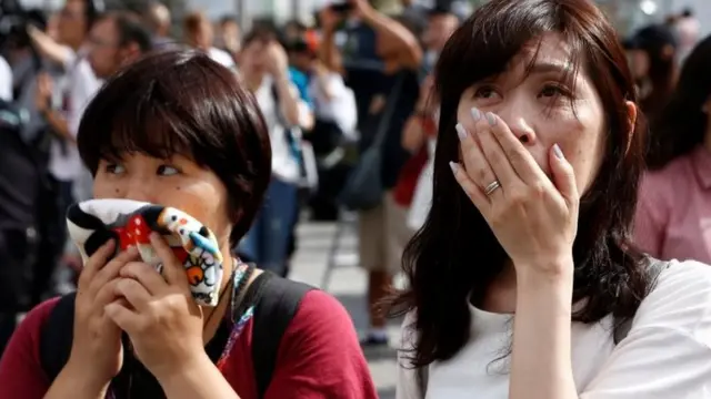 Японки наблюдают за обращением императора к нации