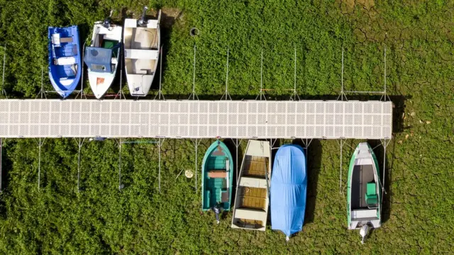 Boats tied to a pier clearly sit on a green background instead of water