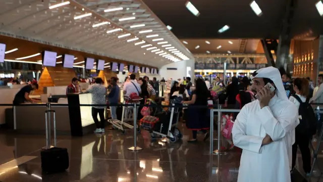 Passengers wait to check-in at a Qatar Airways counter in the Hamad International Airport in the Qatari capital Doha on June 12, 2017