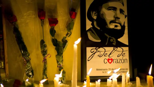 Velas y flores frente a un retrato de Fidel Castro en La Habana
