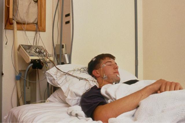 homem dormindo sendo monitorado em cama de hospital