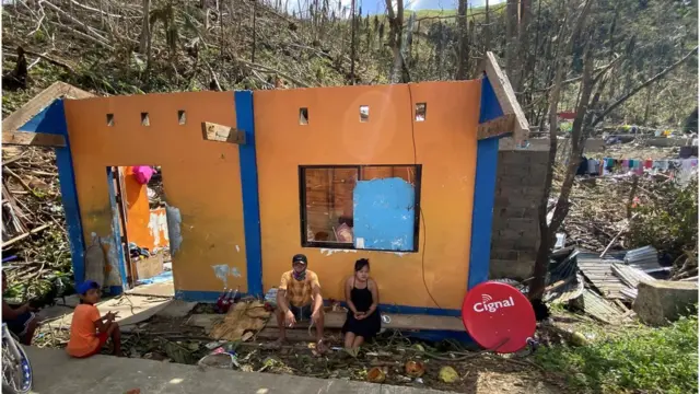 Una pareja sentada frente a las ruinas de su casa en la isla de Siargao, Filipinas, 20 de diciembre de 2021
