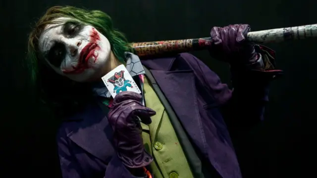 Hombre disfrazado del Guazón con una carta del comodín en la mano.