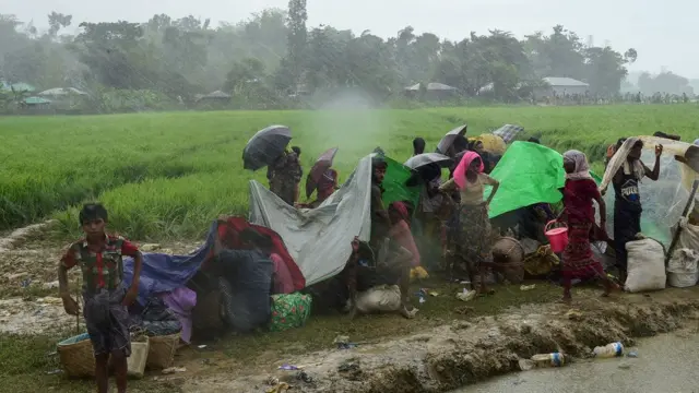 तिरपाल के नीचे बारिश से बचने की कोशिश कर रहे रोहिंग्या परिवार