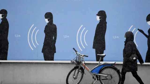 Жена хода поред плаката у Немачкој на коме пише „Најбољи тим. Са дистанце"