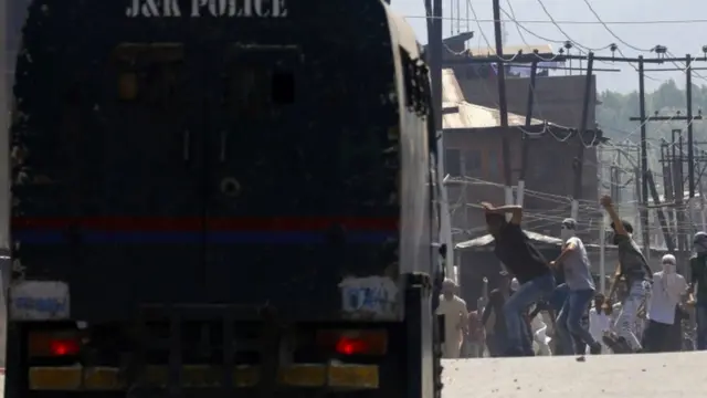 पुलिस वाहन पर पत्थर फेंकते लोग