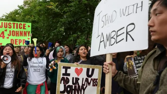 Personas a las afueras de la corte con carteles a favor de Amber Heard.