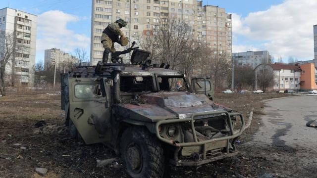 An Ukrainian Territorial Defence fighter examines a destroyed Russian infantry mobility vehicle GAZ Tigr after the fight in Kharkiv on February 27, 2022