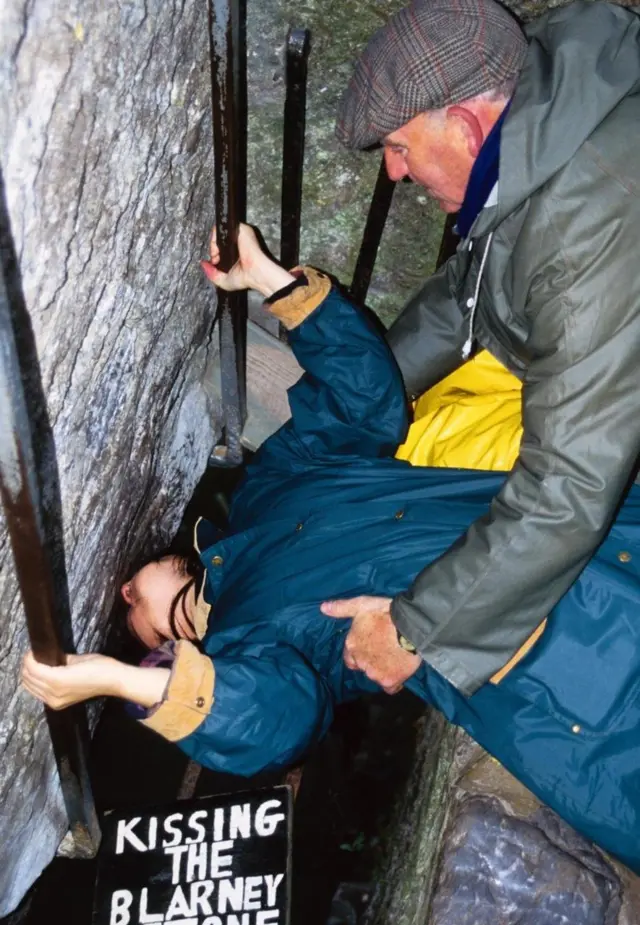 游客在爱尔兰科克附近的布拉尼城堡反身弯腰亲吻布拉尼之石，传说吻了此石后可以变得能言善道